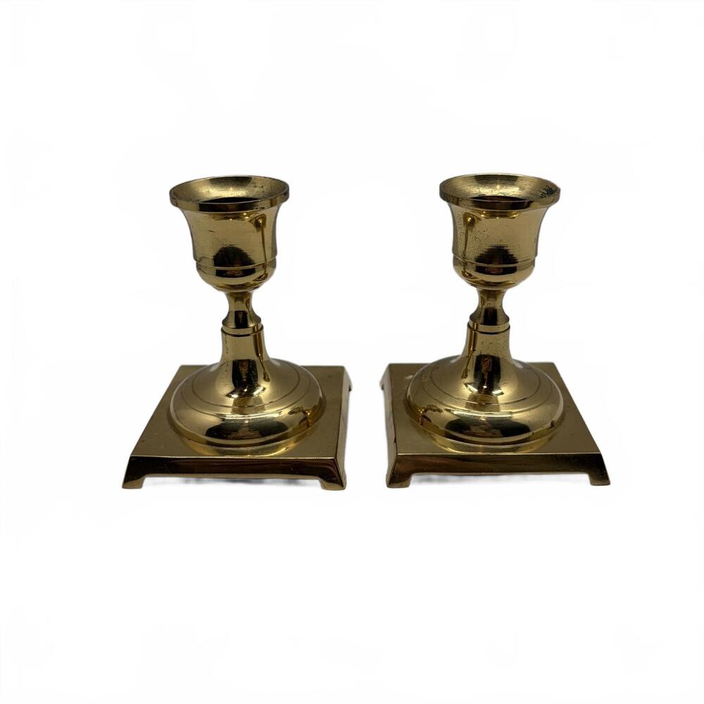 A pair of solid brass candle holders with square bases